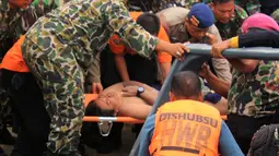 Tim SAR membawa penumpang korban helikopter jatuh yang selamat, Fransiskus Subihardayan (tengah) usai ditemukan mengapung di Danau Toba, Sumatera, Selasa (13/10). Pria itu mengapung setelah dua hari helikopter EC 130 hilang kontak. (AFP PHOTO)