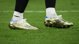 Sepatu Lionel Messi itu sebagian besar berwarna emas, dengan biru dan putih mewakili warna bendera Argentina. Ada pula garis hitam di bagian belakang dan tiga garis putih corak khas Adidas. (AFP/Franck Fife)