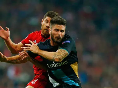 Penyerang Arsenal, Oliver Giroud berebut bola udara dengan gelandang Bayern Muenchen, Xabi Alonso pada lanjutan Grup F liga champions di stadion Allianz Arena, Munich, Jerman (4/11). Muenchen menang atas Arsenal dengan skor 5-1. (Reuters/Michael Dalder) 