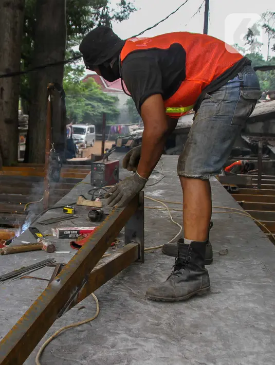 Pekerja menyelesaikan proyek pembangunan jembatan penghubung antarkampung di kawasan Pondok Pinang, Jakarta, Jumat (13/12/2019).  Jembatan yang menghubungkan permukiman di daerah Pondok Pinang dengan kawasan Bintaro tersebut ditargetkan rampung pada akhir Desember. (Liputan6.com/Faizal Fanani)