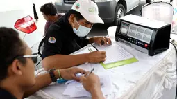 Petugas sudin lingkungan hidup mengisi form uji emisi gas buang kendaraan di kawasan Senayan, Jakarta, Rabu (18/7). Uji emisi gratis dilakukan untuk menekan tingkat pencemaran udara akibat gas buang kendaraan. (Liputan6.com/Immanuel Antonius)