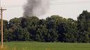 Asap mengepul dari lokasi jatuhnya sebuah pesawat militer milik Amerika Serikat (AS) di jalur county Sunflower-Leflore, negara bagian Mississippi, Senin (10/7). Setidaknya lima orang tewas dalam insiden ini. (AP Photo/Andy Lo)