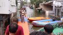 Warga berjalan melintasi jembatan apung saat banjir melanda Perumahan Periuk Damai, Tangerang, Banten, Selasa (23/2/2021). Adanya jembatan apung mempermudah warga saat melintasi banjir setinggi 2,5 meter di tempat tersebut. (Liputan6.com/Angga Yuniar)