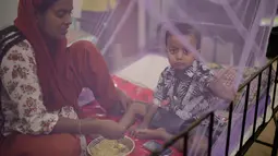 Seorang wanita memberi makan anaknya yang menjadi pasien demam berdarah di Rumah Sakit Shishu Dhaka, Bangladesh, Rabu (31/7/2019). Banyak rumah sakit dibanjiri pasien penyakit tersebut sehingga semakin membebani sistem layanan medis yang saat ini sudah kewalahan. (AP Photo/Mahmud Hossain Opu)