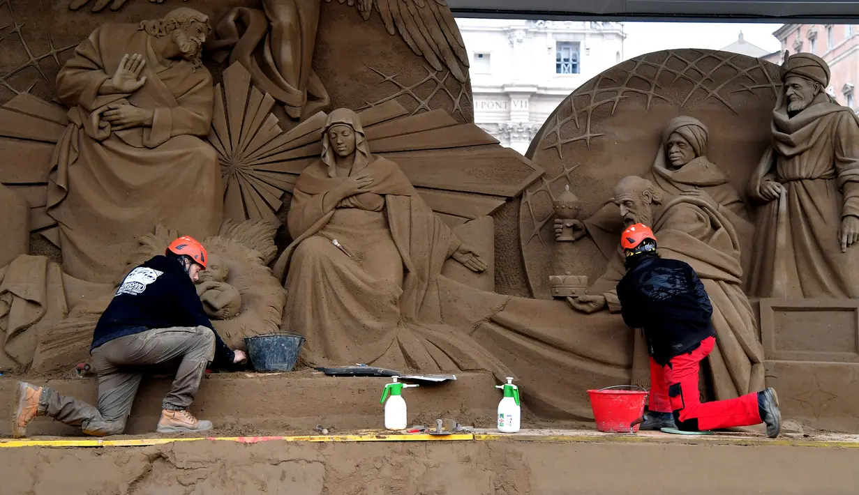 Seniman Rusia Ilya Filimontsev (kiri) dan seniman Ceko Radovan Zivny (kanan) saat membuat patung pasir adegan kelahiran Yesus di St Peter, Vatikan, Kamis (6/12). Patung ini dipersiapkan untuk menyambut Natal. (Tiziana FABI/AFP)