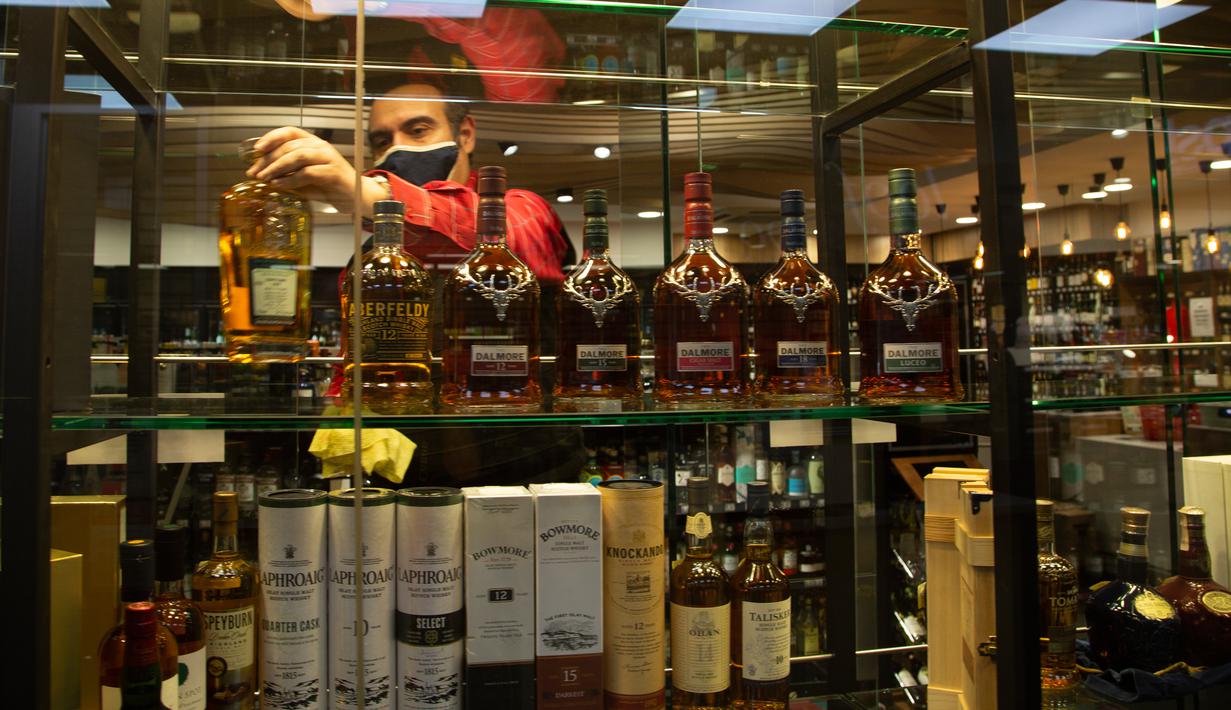 Seorang pria mengisi rak pajangan dengan botol alkohol di sebuah toko ketika Afrika Selatan mencabut larangan penjualan alkohol dan rokok di Johannesburg, Selasa (18/8/2020). Pembelian alkohol dan rokok dilarang ketika Afsel memberlakukan lockdown ketat pada 27 Maret 2020. (AP Photo/Denis Farrell)