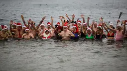 Anggota klub renang "Berliner Seehunde" (Berlin Seals mengenakan topi bertema Natal saat berenang di Danau Orankesee, Berlin yang dingin, Senin (25/12). Berenang di danau itu salah satu tradisi di Berlin menyambut Natal setiap tahun. (AP/Markus Schreiber)