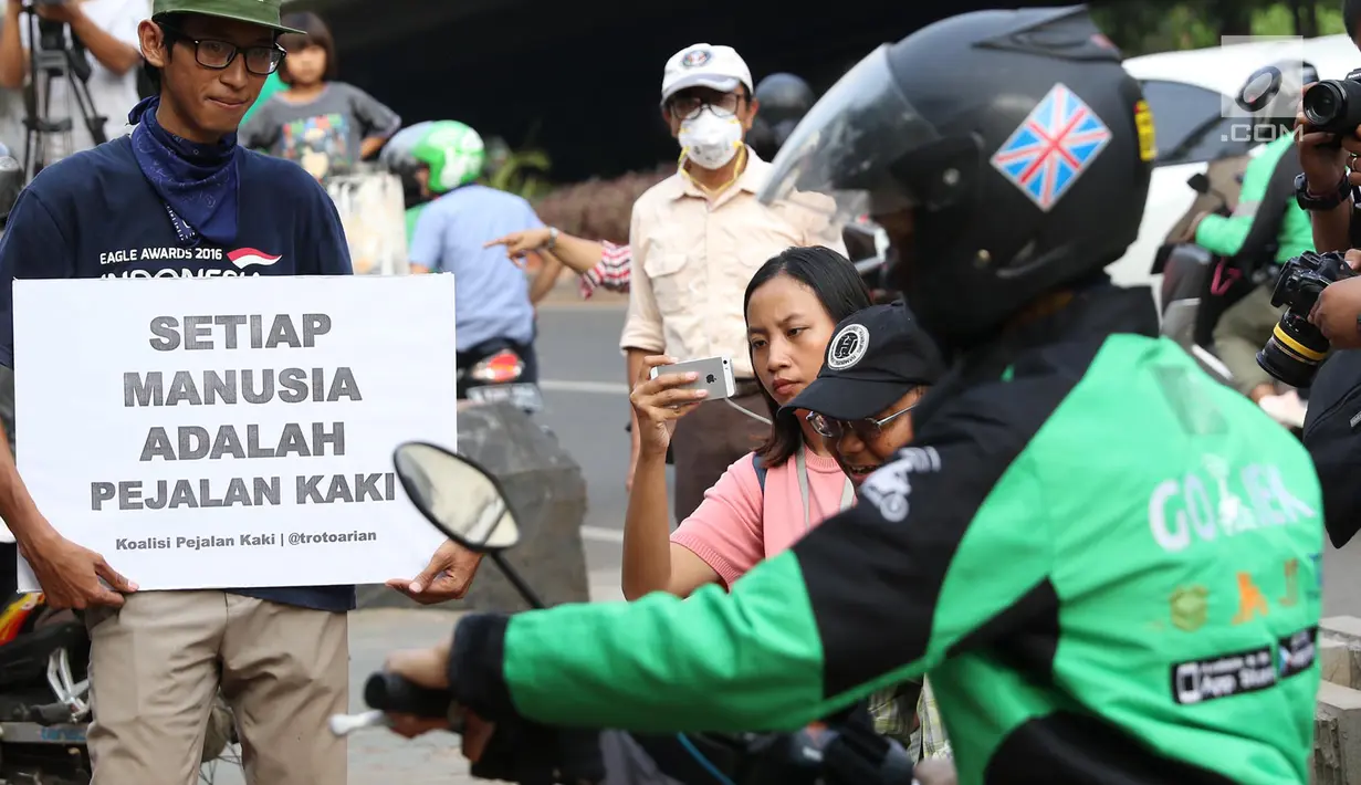 Aktivis Koalisi Pejalan Kaki (KPK) membawa poster himbauan saat menghadang pengendara sepeda motor yang menerobos trotoar di depan Tempat Pemakaman Umum (TPU) Menteng Pulo, Jalan Casablanca, Jakarta Selatan, Jumat (21/7). (Liputan6.com/ Immanuel Antonius)