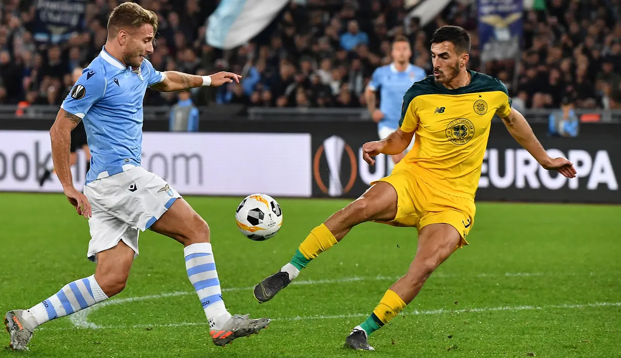 Pemain Lazio Ciro Immobile berebut bola dengan bek Celtic, Hatem Abd Elhamed pada matchday keempat Grup E Liga Europa 2019 di Stadion Olympico, Kamis (7/11/2019). Celtic mengalahkan Lazio 2-1 untuk kemudian melaju ke babak 32 besar. (Tiziana FABI / AFP)