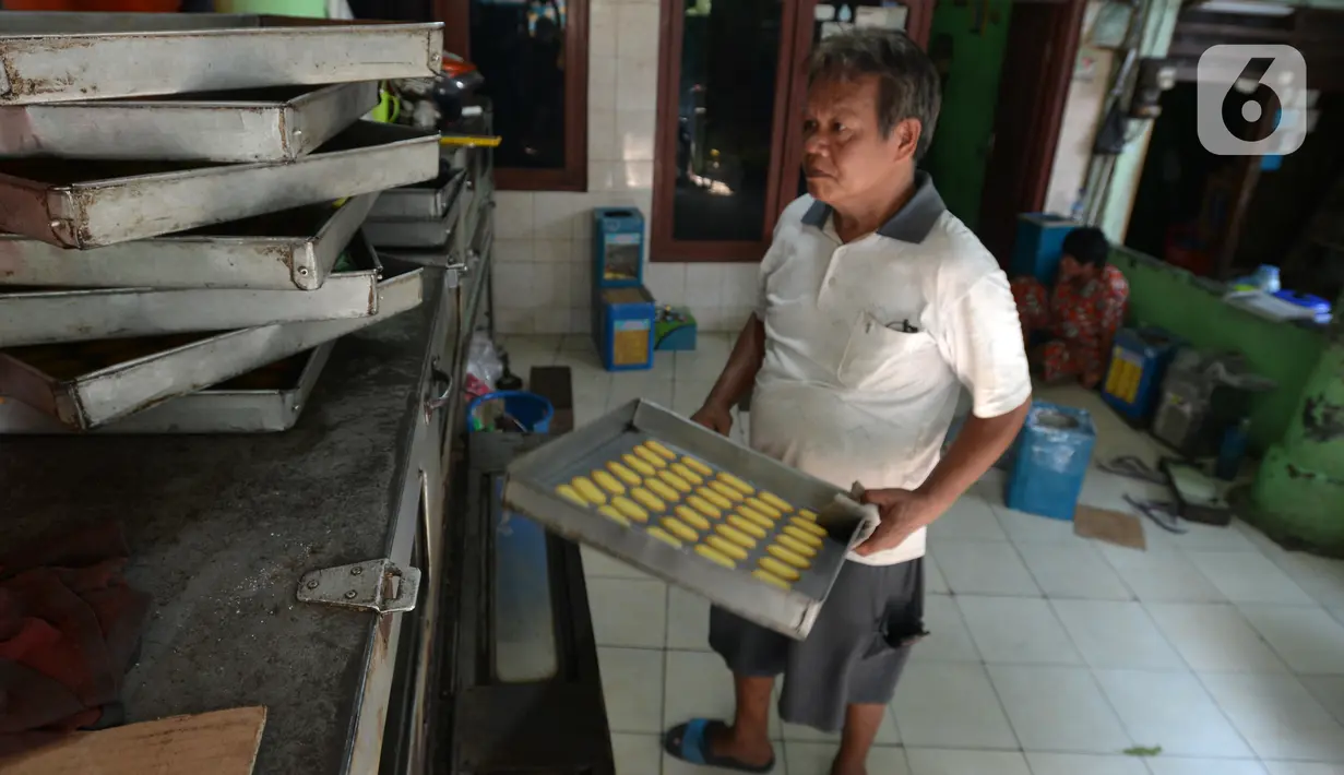 Pekerja membawa adonan kue kering untuk dipanggang dalam oven di usaha pembuatan kue Pusaka Kwitang di kawasan Kwitang, Jakarta Pusat, Selasa (27/4/2021). Pada masa pandemi COVID-19, usaha milik Hasanudin ini masih memenuhi stok walau tidak banyak permintaan dari para agen. (merdeka.com/Imam Buhori)