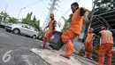 Petugas memindahkan pot saat akan menambal jalan berlubang di wilayah Pasar Senen, Jakarta, Selasa (26/7). Penambalan jalan berlubang ini bertujuan untuk kenyamanan pengguna jalan yang melintas. (Liputan6.com/Yoppy Renato)