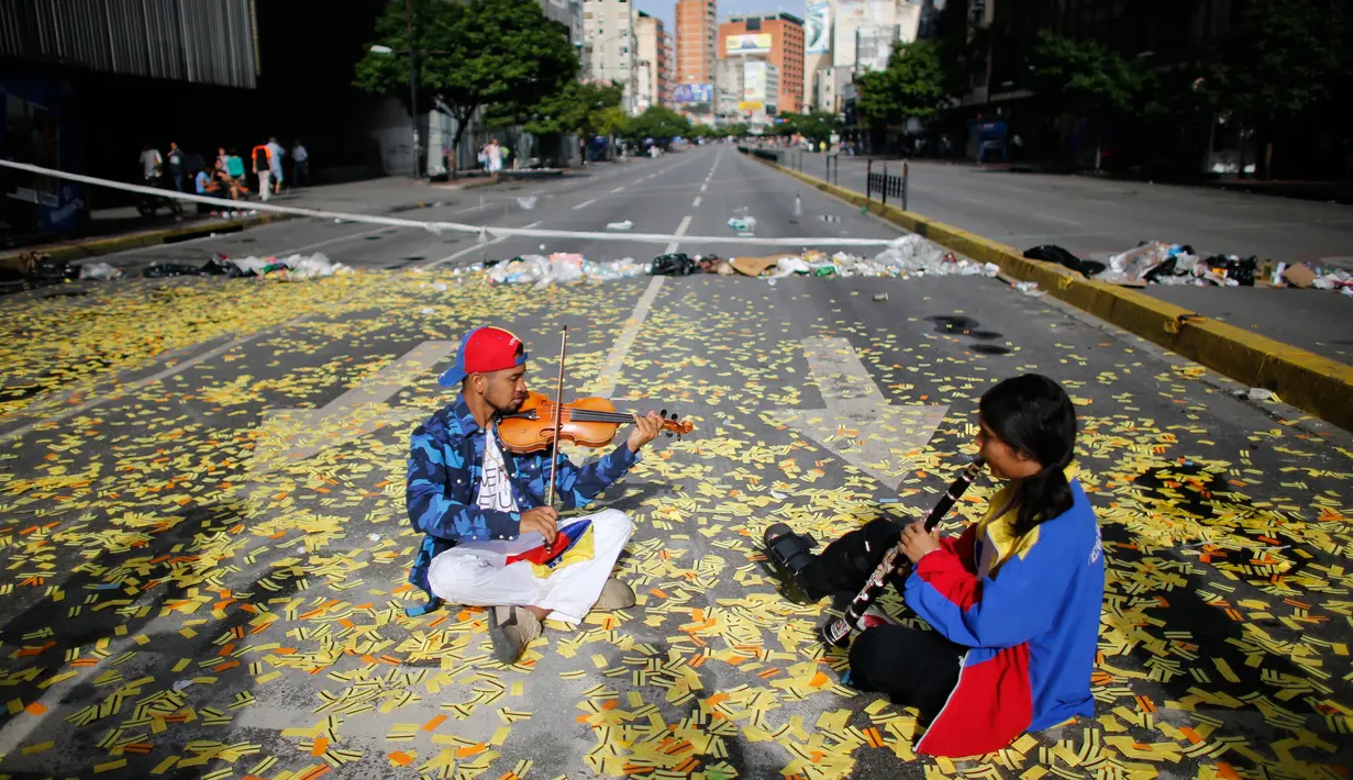 Musisi memainkan alat musiknya saat unjuk rasa memprotes anti-pemerintah Nicolas Maduro di Caracas, Venezuela, (20/7). Hingga kini, bentrokan antara demonstran dan polisi masih terjadi. (AP Photo/Ariana Cubillos)
