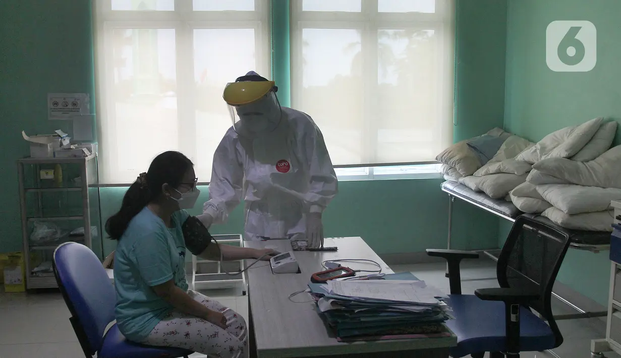 Paramedis melakukan observasi kepada seorang pasien positif COVID-19 yang dirawat di Puskesmas Jurumudi, Tangerang, Banten, Kamis (17/2/2022). Kasus positif COVID-19 di Kota Tangerang terus mengalami penurunan kasus dari 2000 kasus perhari menjadi 1000 kasus perhari. (merdeka.com/Arie Basuki)