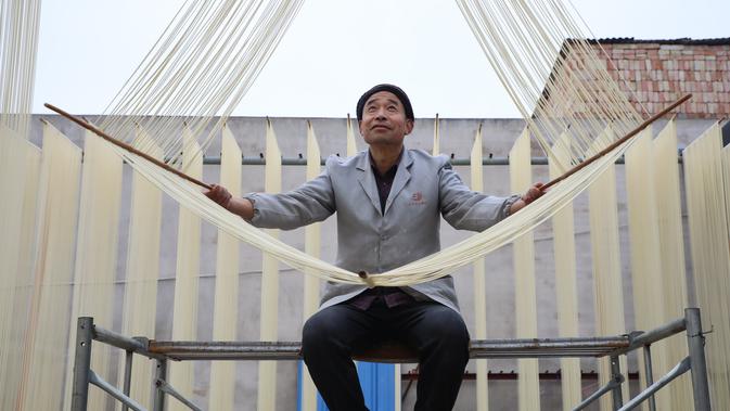 Seorang penduduk desa membentangkan mi di Desa Huangjiazhuang di Distrik Maiji, Kota Tianshui, Provinsi Gansu, China barat laut, pada 30 November 2020. Proses pembuatan mi di desa tersebut memiliki sejarah lebih dari 200 tahun. (Xinhua/Ma Xiping)