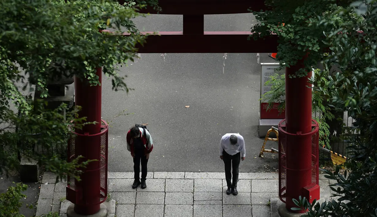Seorang pria yang mengenakan masker pelindung untuk membantu mengekang penyebaran virus corona COVID-19 sebelum menaiki tangga curam sebuah kuil di Tokyo, Jepang, Senin (12/10/2020). Tokyo mengonfirmasi lebih dari 70 kasus COVID-19 pada hari Senin. (AP Photo/Eugene Hoshiko)