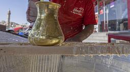 Pembuat penganan Mesir Mostafa Anwar membuat makanan penutup tradisional yang disebut "Kunafa" sebelum berbuka puasa, di kiosnya di ibu kota Kairo pada 14 April 2022.  Kunafa merupakan hidangan pencuci mulut utama di kalangan orang Arab selama Ramadhan berlangsung. (Khaled DESOUKI/AFP)