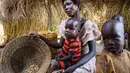 Alissa Lual bersama tiga anaknya menunjukkan persedian makanan di dalam penampungan di Sudan Selatan (22/11). Kini mereka menderita krisis air bersih dan kelaparan karena minimnya persediaan pangan. (AFP Photo/Albert Gonzalez Farran)