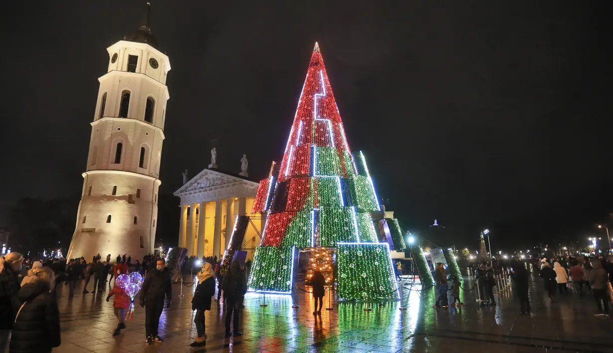 Pohon Natal yang menyala terlihat di dekat katedral di Vilnius, Lithuania pada 28 November 2020. Pohon natal raksasa yang dihiasi berbagai ornamen lampu hias tersebut membuat kawasan di ibu kota Lithuania menjadi terang. (PETRAS MALUKAS / AFP)