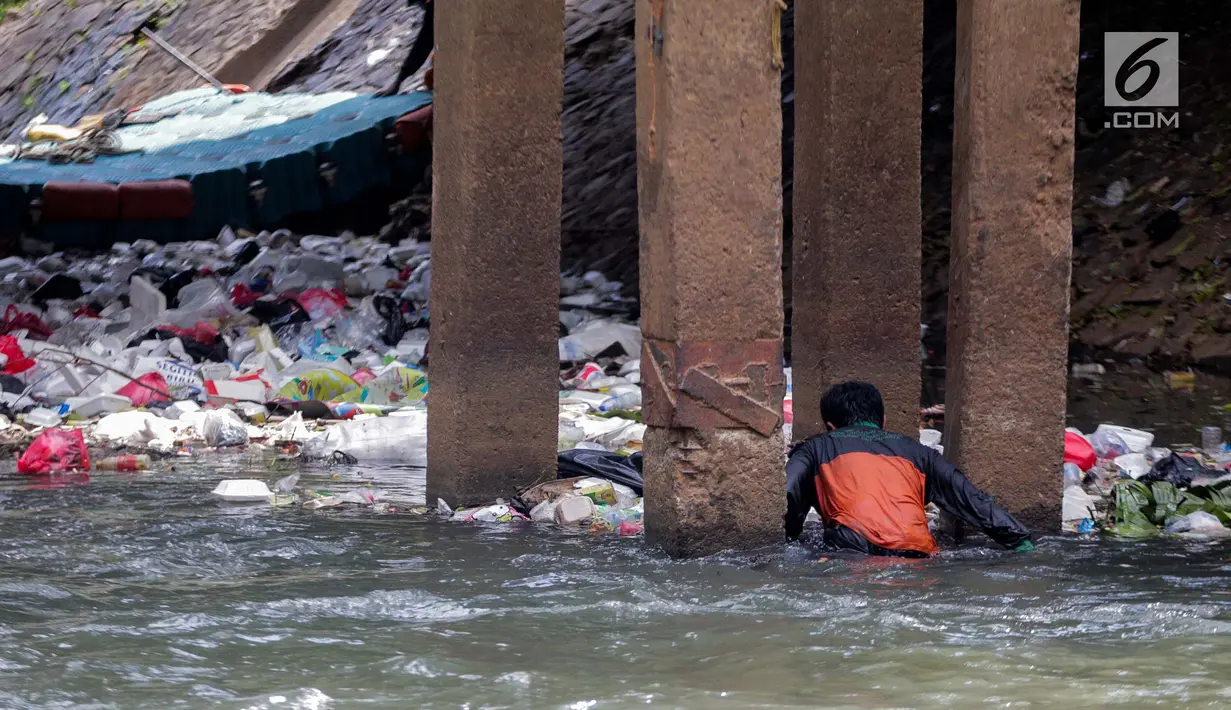 Aksi petugas PPSU bersihkan sampah yang tersangkut ditengah deras arus aliran anak kali Ciliwung, Jakarta, Senin (22/7/2019). Pembersihan sungai dari berbagai sampah tersebut dimaksudkan agar tidak ada penumpukan sampah dan sedimentasi saluran di sepanjang sungai. (Liputan6.com/Faizal Fanani)