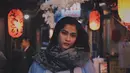 Berpose di jalanan Tokyo dengan latar lampion di depan kedai khas Jepang, wanita kelahiran tahun 1997 ini menggunakan busana berwarna tenang. Kali ini syal berwarna abu-abu bermotif gelap melindungi lehernya dari kedinginan. (Liputan6.com/IG/@aghninyhaque)