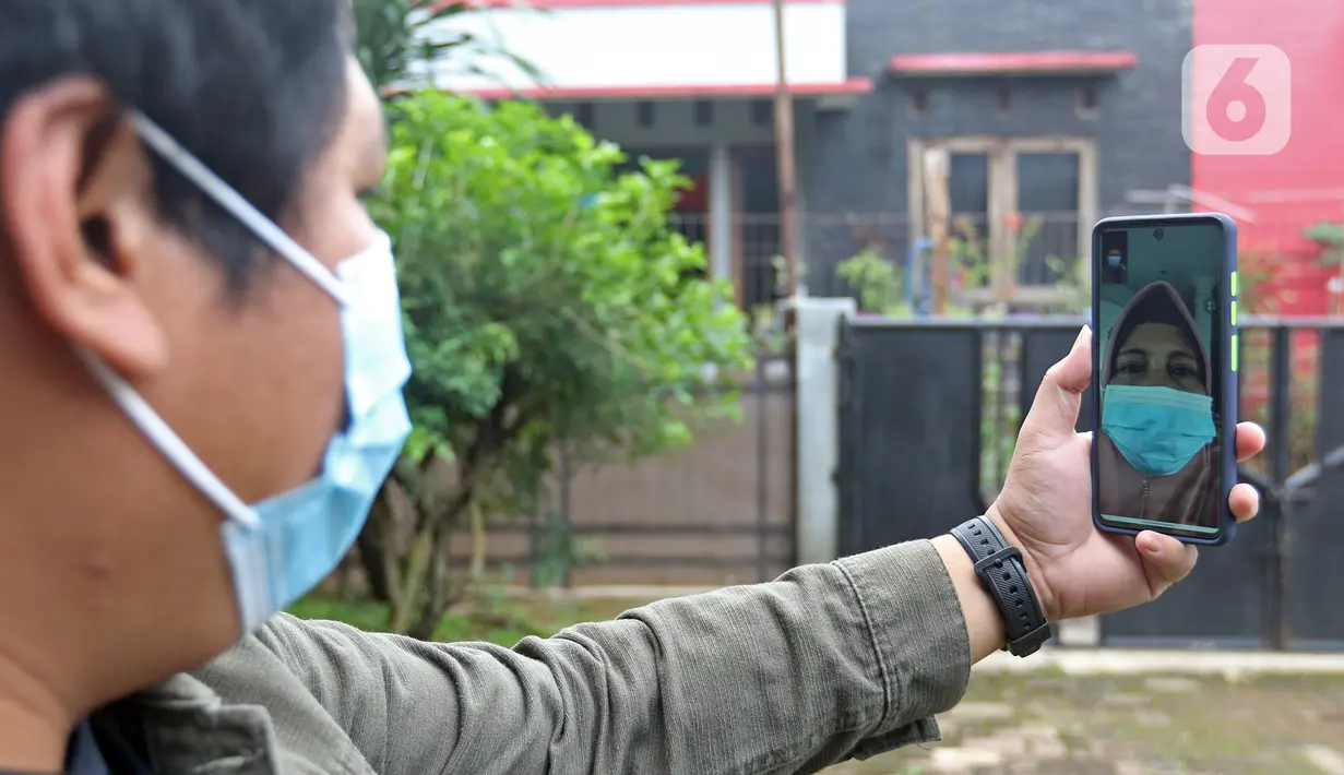 NY yang sedang melakukan isolasi mandiri karena terjangkit COVID-19 melakukan panggilan video dengan anaknya dari kediamannya, Rabu (10/2/2021). NY mengaku sudah rindu kembali bertugas sebagai tenaga kesehatan, garda terdepan yang menangani para pasien COVID-19. (Liputan6.com/Herman Zakharia)