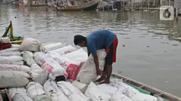 Pekerja mengangkut barang menggunakan perahu menuju dermaga di Desa Pantai Mekar, Muaragembong, Kabupaten Bekasi, Senin (6/12/2021). Jasa angkut barang menggunakan perahu tersebut bertarif Rp 3.000 per 15 kg. (Liputan6.com/Herman Zakharia)