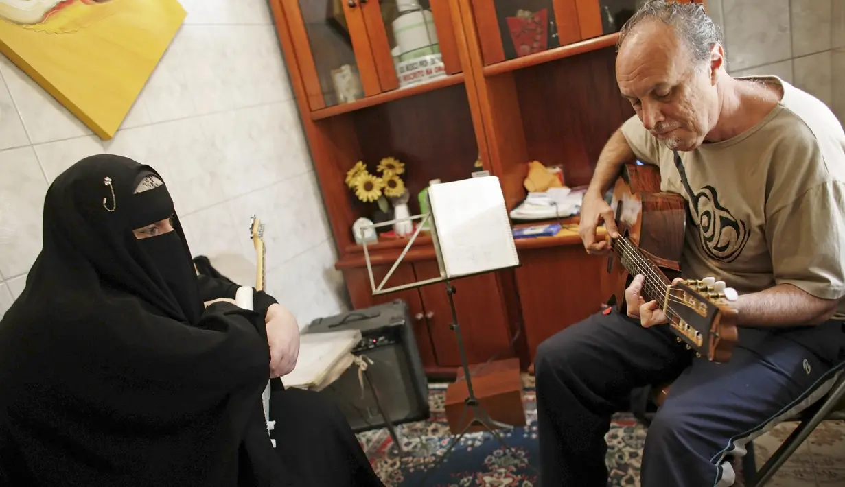 Gisele Marie melihat gurunya Marcelo (kanan) memainkan gitar selama kelas musik di Sao Paulo, Brasil (13/8/2015). Marie merupakan cucu dari kakek beragama Katolik Jerman, ia masuk Islam setelah ayahnya meninggal pada tahun 2009. (REUTERS/Nacho Doce)