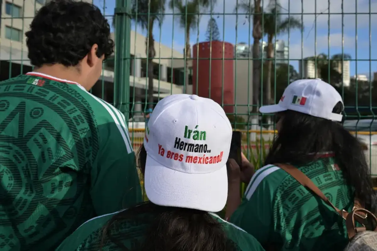 Para penggemar sepak bola di Meksiko menunggu tim Iran sambil mengenakan topi bertuliskan, 'Iran, saudaraku, kau sekarang orang Meksiko', di luar hotel tim di Tijuana, Meksiko, pada 27 Juni 2026. (Dok. AFP/Guillermo Arias)