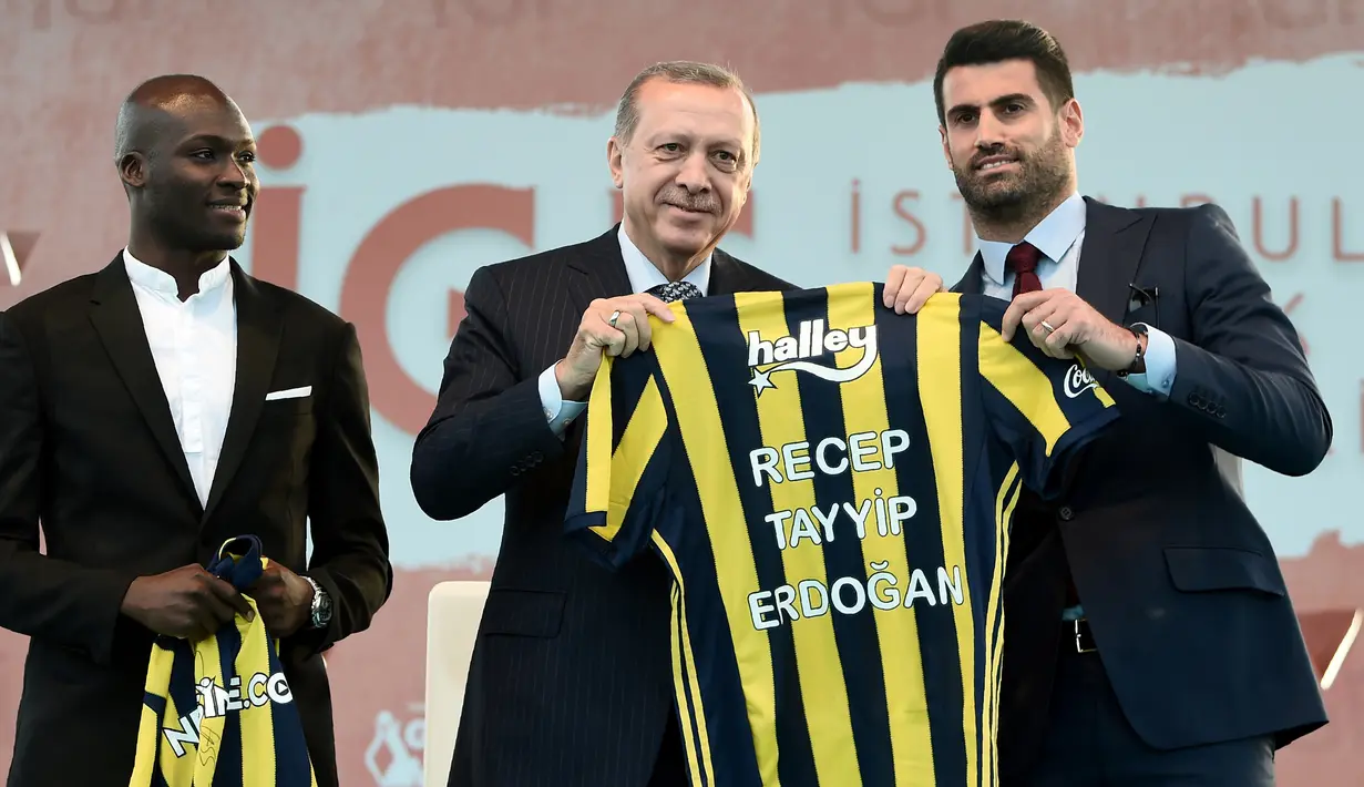 Presiden Turki, Recep Tayyip Erdogan (tengah) memegang jersey atas namanya ditemani pesepak bola dari Fenerbahce, Mousa Sow (kiri) dan Volkan Demirel (kanan) saat menghadiri Istanbul Youth Festival di Istanbul, Turki, Kamis (4/5). (AFP PHOTO / OZAN KOSE)