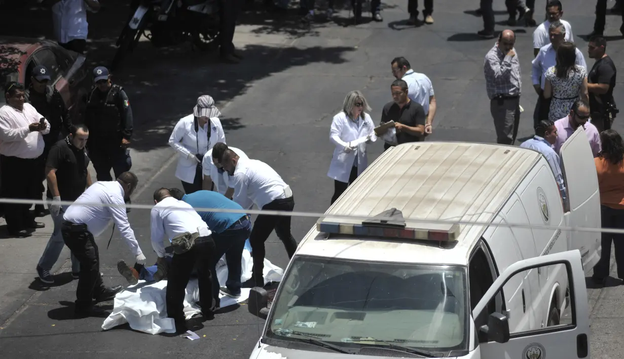 Petugas forensik dan ambulan bersiap mengevakuasi mayat seorang jurnalis senior Meksiko, Javier Valdez, yang tewas dibunuh di ibu kota negara bagian, Culiacan, Senin (15/5). Valdez merupakan jurnalis kelima yang dibunuh di Meksiko. (FERNANDO BRITO/AFP)