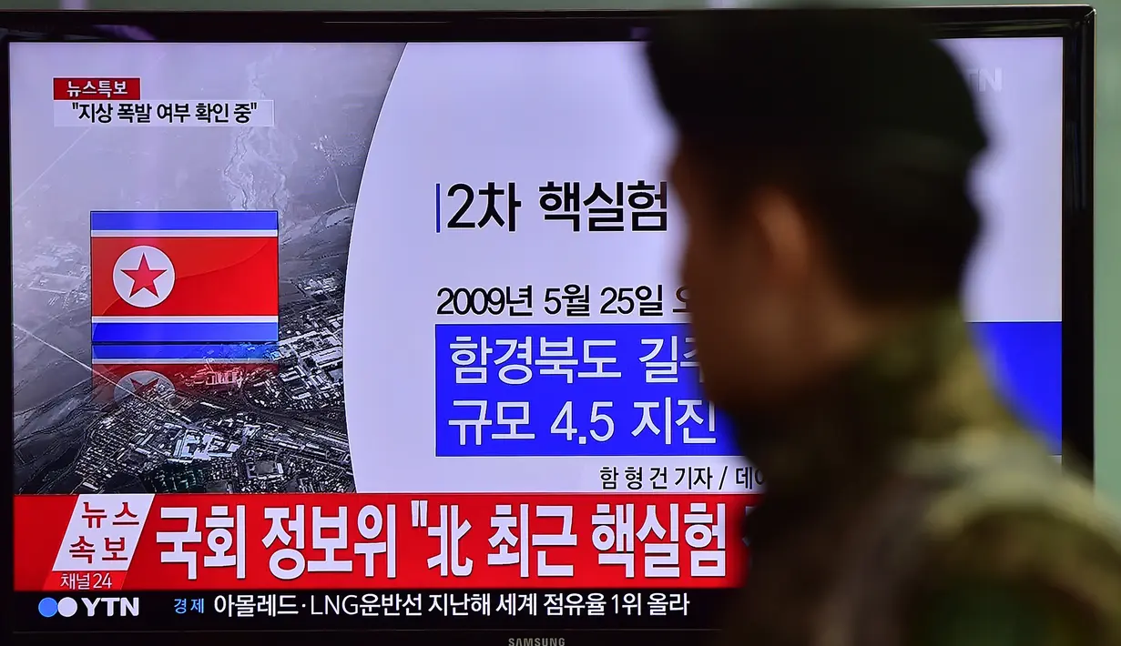 Tentara Korea Selatan berjalan melewati sebuah layar TV yang menunjukkan laporan berita di sebuah stasiun kereta api di Seoul, Rabu (6/1/2016). Gempa berkekuatan 5,1 SR terdeteksi di dekat tempat uji coba nuklir Korea Utara. (AFP PHOTO/Jung Yeon-Je)