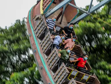 Pengunjung yang mengenakan masker menikmati wahana di taman hiburan Enchanted Kingdom di Provinsi Laguna, Filipina (18/10/2020). Taman hiburan tersebut kembali dibuka untuk pengunjung. (Xinhua/Rouelle Umali)