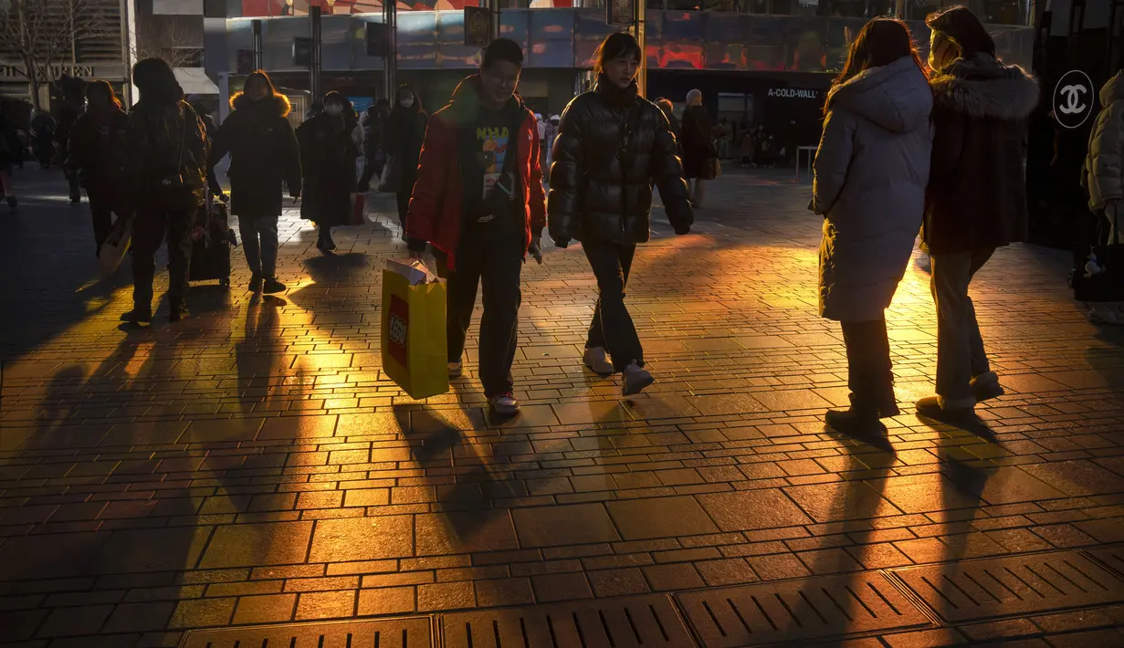 Pengunjung diterangi oleh pantulan sinar matahari saat mereka berjalan melalui pusat perbelanjaan pada hari terakhir minggu liburan Tahun Baru Imlek di Beijing, Jumat, 27 Januari 2023. (AP Photo/Mark Schiefelbein)