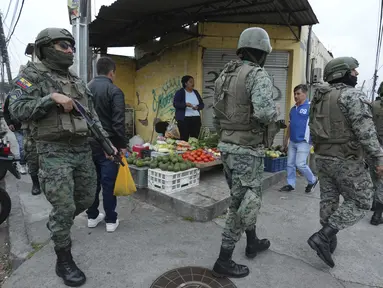Tentara berpatroli di sekeliling penjara Inca selama keadaan darurat saat seorang penjual makanan berjualan di trotoar di Quito, Ekuador, Aetelah kaburnya seorang pemimpin geng yang berkuasa dari penjara, Selasa, 9 Januari 2024. (AP Photo/Dolores Ochoa)
