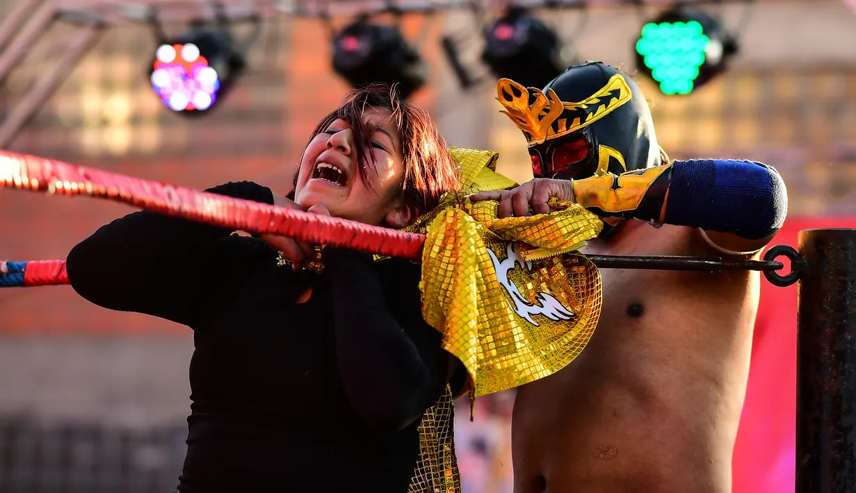Pegulat Bolivia, Blanca Perez dikunci oleh lawannya pegulat pria di atas ring gulat di El Alto, pada 24 November 2019. Di Bolivia ada sebuah atraksi gulat yang diperankan perempuan dengan menggunakan busana khas warga Bolivia. (Ronaldo SCHEMIDT / AFP)