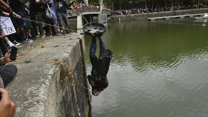 Demonstran melempar patung pedagang budak Edward Colston ke Pelabuhan Bristol saat protes Black Lives Matter di Bristol, Inggris, Minggu (7/6/2020). Aksi tersebut dilakukan sebagai bentuk protes atas kematian George Floyd saat ditangkap oleh polisi di Amerika Serikat. (Ben Birchall/PA via AP)