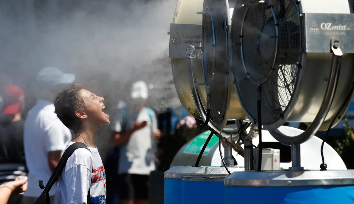 Seorang penonton berdiri di depan kipas angin saat menyaksikan kejuaraan tenis Australian Open 2017 di Melbourne, Australia (16/1). (AP Photo / Kin Cheung)