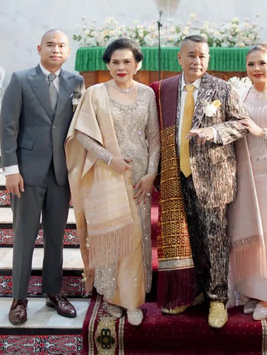 Saat pernikahan sang adik, Felicia mengenakan kebaya rancangan Myrna Myura itu memiliki potongan asimetris dan detail sweetheart neckline warna soft pink. Dipadukan selendang dan bawahan ulos. [@djanurms.mua/@myrnamyura]