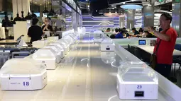 Pengunjung mengambil gambar sejumlah robot pintar sebesar oven microwave di restoran Robot.He milik Alibaba di Shanghai, 30 Juli 2018. Tugas robot itu mengangkat tutup kaca hidangan bergaya Shanghai dan mengucapkan, "Selamat menikmati hidanganmu". (AFP)