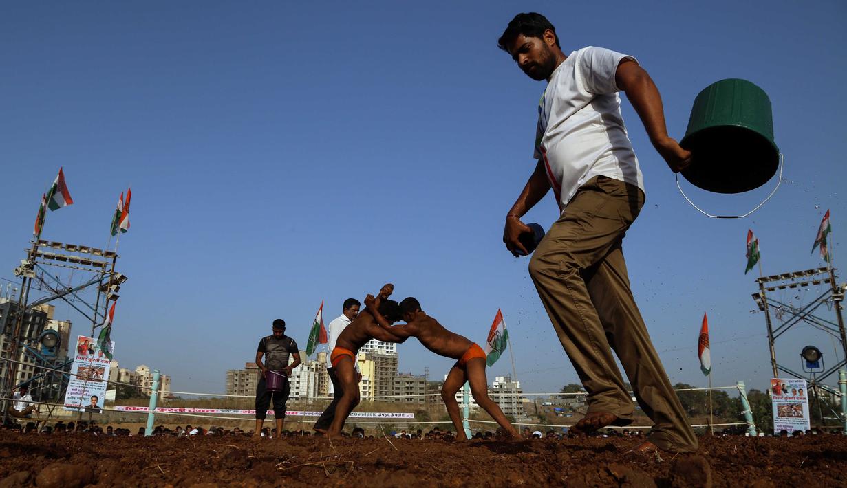Panitia menyiram areal pertandingan Indian traditional wrestling competition atau Kushti di Arena Akhara, Mumbai, India, 20 Maret 2016.  Olahraga tradisional ini terus dilestarikan sebagai bagian dari budaya. (EPA/Divyakant Solanki)