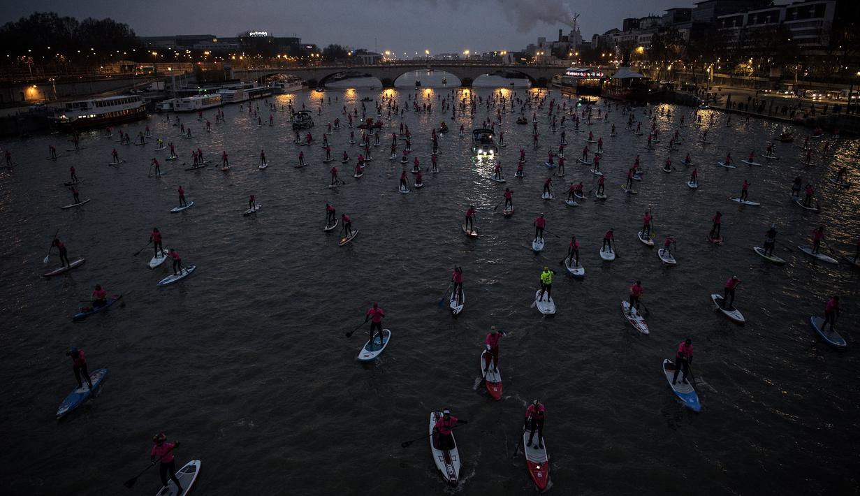 Para peserta ambil bagian dalam perlombaan dayung sambil berdiri pada Nautic SUP Paris di sepanjang sungai Seine, Paris, Minggu (3/12). Sekitar 700 peserta berpartisipasi menyeberangi sungai Seine dengan pemandangan kota Paris (AFP PHOTO/CHRISTOPHE SIMON)
