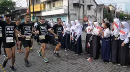 Siswi SMP memberi semangat kepada pelari yang mengikuti Semarang 10K di Kota Semarang, Jawa Tengah, Minggu (16/12). Ribuan pelari dari berbagai daerah di Indonesia ikut meramaikan lomba ini. (Liputan6.com/Gholib)