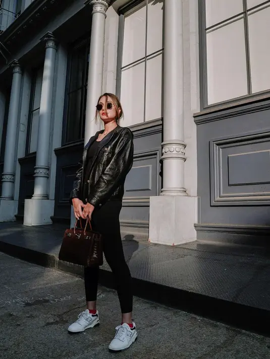 Luna Maya mengenakan all black outfit saat berlibur. Di dalam foto ini, ia tampak mengenakan tank top hitam, ditumpuknya dengan black leather jacket, dan legging hitam. Ia menyempurnakan gayanya di sini dengan sunglasses dan sneakers putih. Foto: Instagram.