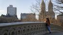 Seorang pengunjung berjemur di bawah sinar matahari di Bow Bridge di Central Park, wilayah Manhattan, New York, Senin (30/1/2023). Terakhir kali butuh waktu lama sebelum salju bertahan di tanah pada musim dingin adalah tahun 1973, ketika warga New York harus menunggu hingga 29 Januari. (AP Photo/John Minchillo)