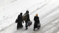 Warga Suriah berjalan di jalan yang tertutup salju di kota Maaret al-Numan, di provinsi utara Idlib, Suriah, pada 21 Desember 2016 (AFP Photo)