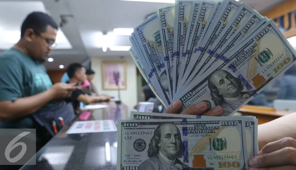 Petugas menunjukkan mata uang Dolar Amerika di toko penukaran uang di Jakarta, Selasa (7/6). Dolar AS kembali melemah terhadap rupiah. Mata uang Paman Sam ini bergerak dikisaran Rp 13.300. (Liputan6.com/Angga Yuniar)