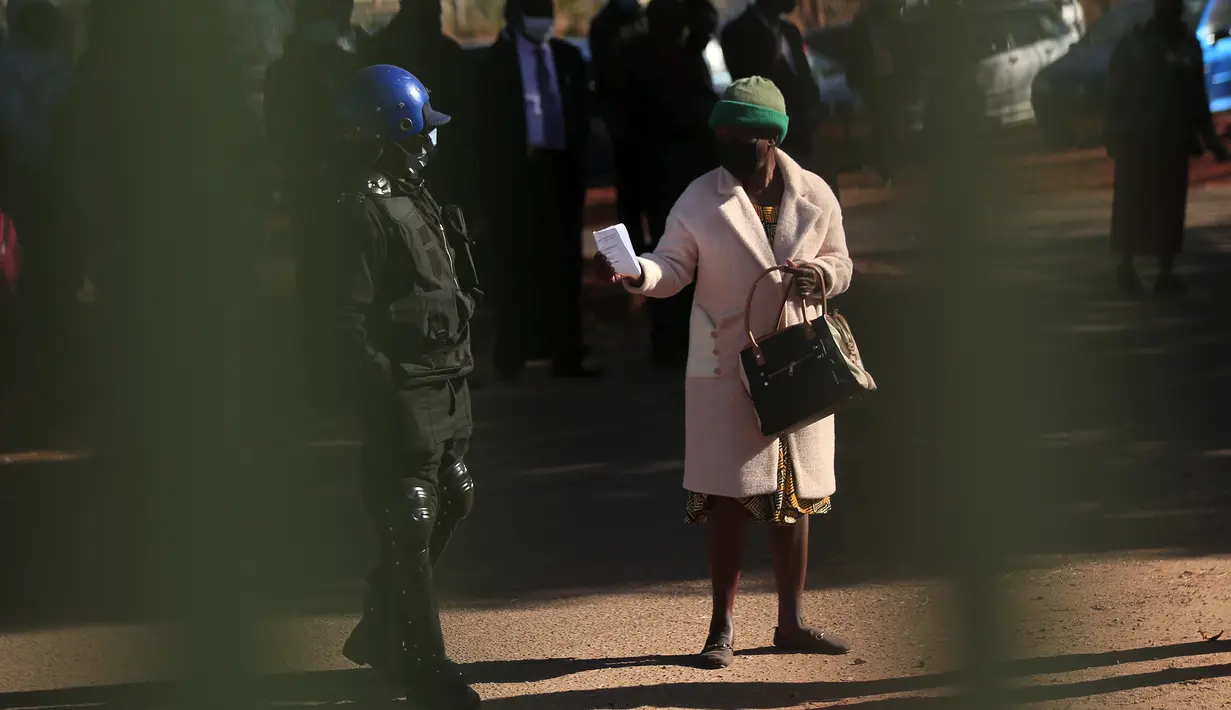 Petugas polisi memeriksa izin masuk seorang pejalan kaki di Harare (22/7/2020). Presiden Zimbabwe Emmerson Mnangagwa mengumumkan sederet kebijakan karantina lockdown, termasuk penerapan jam malam mulai pukul 18.00-06.00 waktu setempat, guna meredam lonjakan kasus COVID-19. (Xinhua/Shaun Jusa)