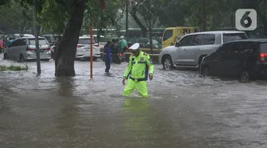 Polisi mengecek ketinggian genangan banjir yang menutupi Jalan Letjen Suprapto, Cempaka Putih, Jakarta Pusat, Kamis (29/2/2024). (merdeka.com/Arie Basuki)