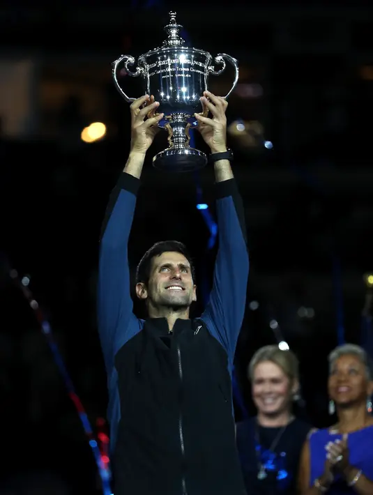 Petenis Serbia, Novak Djokovic mengangkat trofi AS Terbuka usai mengalahkan Juan Martin del Potro pada partai final di New York, Minggu (9/9). Gelar ini adalah yang keempat di AS Terbuka sejak yang terakhir pada 2015. (MATTHEW STOCKMAN/GETTY IMAGES/ AFP)