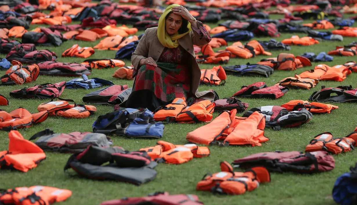 Seorang wanita di antara jaket pelampung yang dipajang di dekat Gedung Parlemen London, Senin (19/9). Sebanyak 2.500 jaket pelampung yang usang ini pernah dipakai para pengungsi yang menyebrang dari Turki ke Pulau Chios, Yunani. (Daniel Leal-Olivas/AFP)
